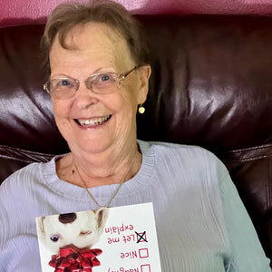 A woman smiling as she opens the humorous "Let Me Explain" dog-themed Christmas card.