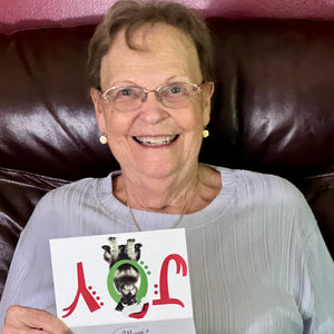 Smiling woman holding a Christmas card featuring a Schnauzer dog, expressing joy and excitement upon receiving the holiday greeting.