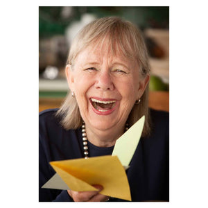 Woman smiling and laughing as she opens a humorous cow-themed birthday card.