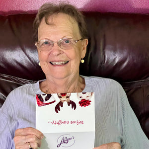 Smiling woman receiving a funny dog-themed Christmas card during holiday celebration