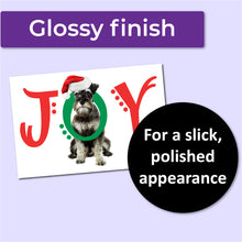 Load image into Gallery viewer, A white Christmas card with a schnauzer dog on the front with the word JOY. The J and Y are red, and the O is green and wrapped around the dog&#39;s neck. A purple banner at the top that says, &quot;Glossy finish&quot; and a black circle with text that says, &quot;For a slick, polished appearance.&quot;
